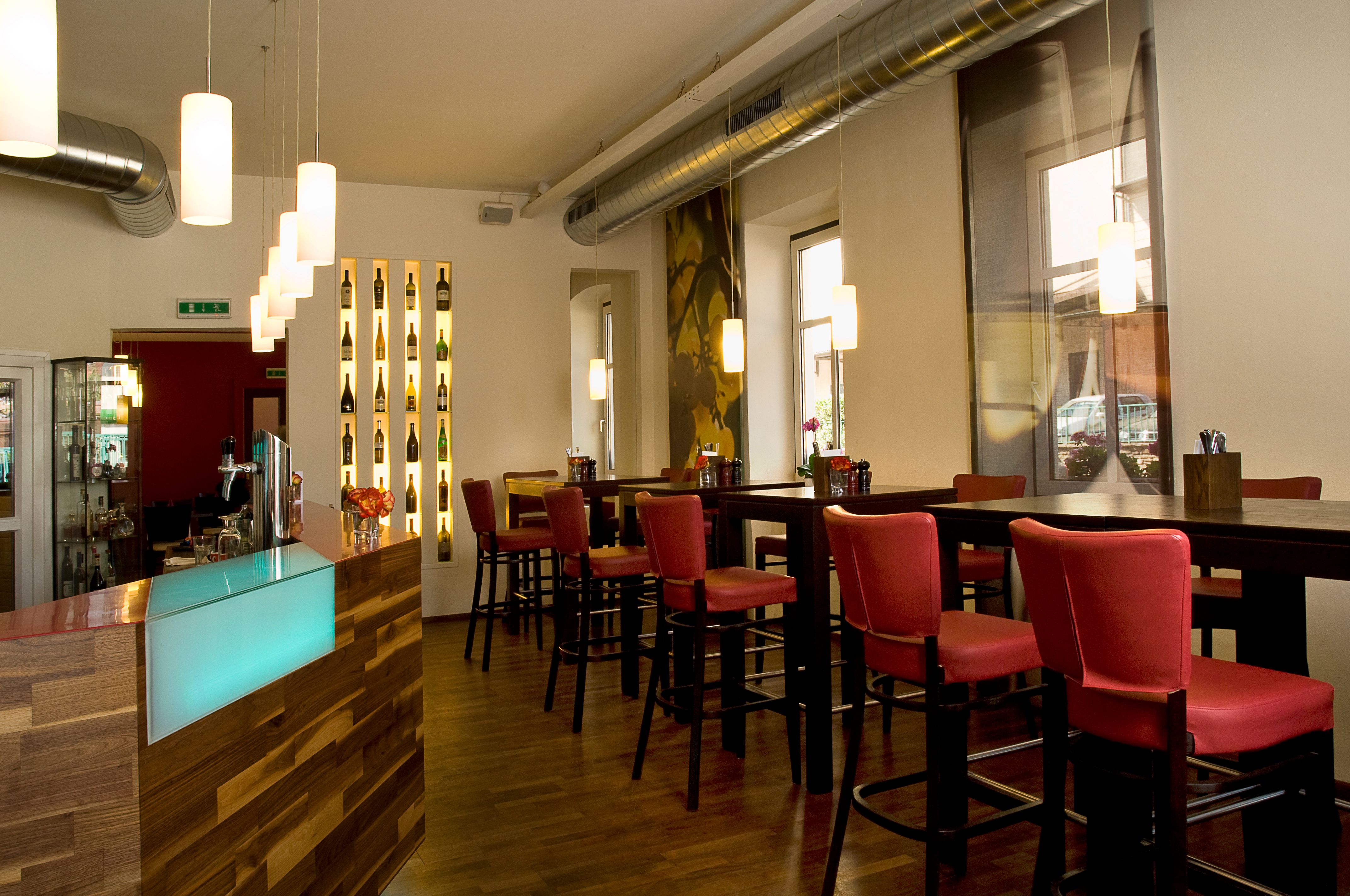 Pohľad do interiéru modernej reštaurácie s červenými stoličkami a dreveným pultom.