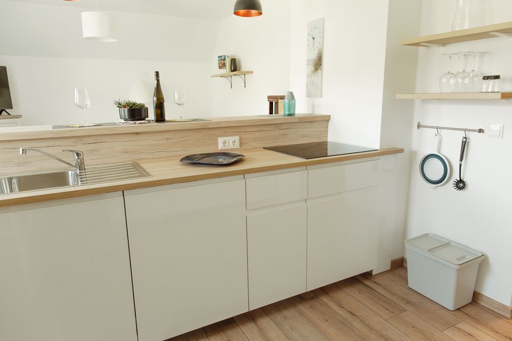 Moderná kuchyňa s drevenou pracovnou doskou, drezom, varnou doskou a policami na poháre.