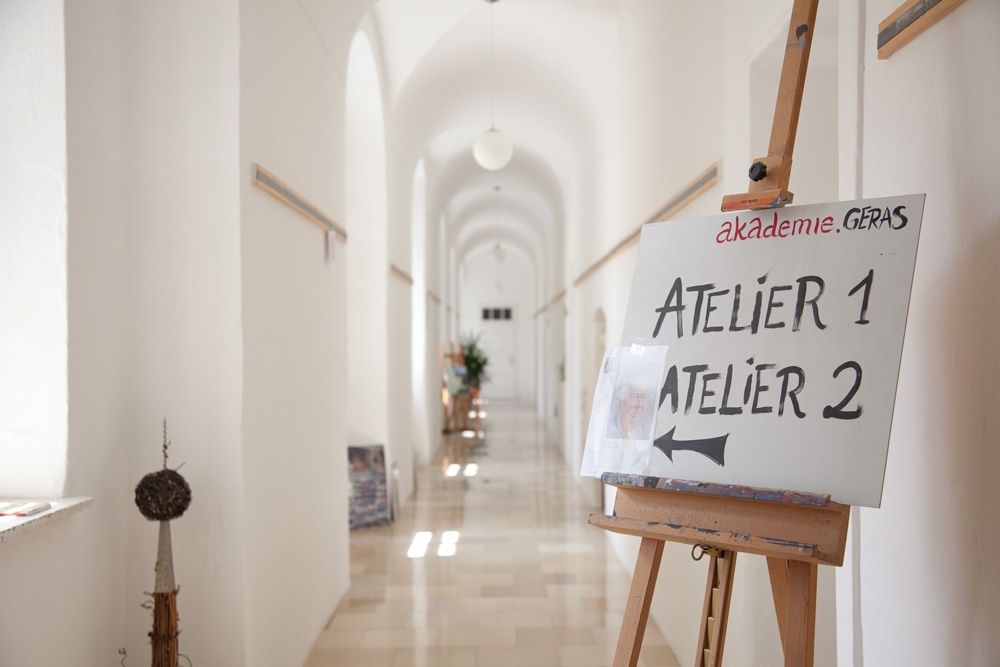 Svetlá chodba s nápisom na stojane, ktorý ukazuje na ateliér 1 a ateliér 2.