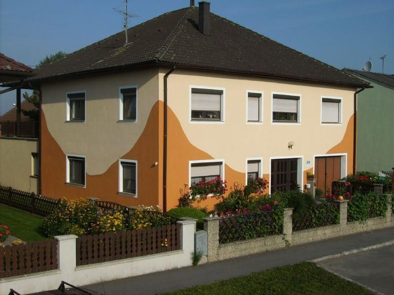 Dvojpodlažný dom s oranžovo-béžovou fasádou a záhradou.