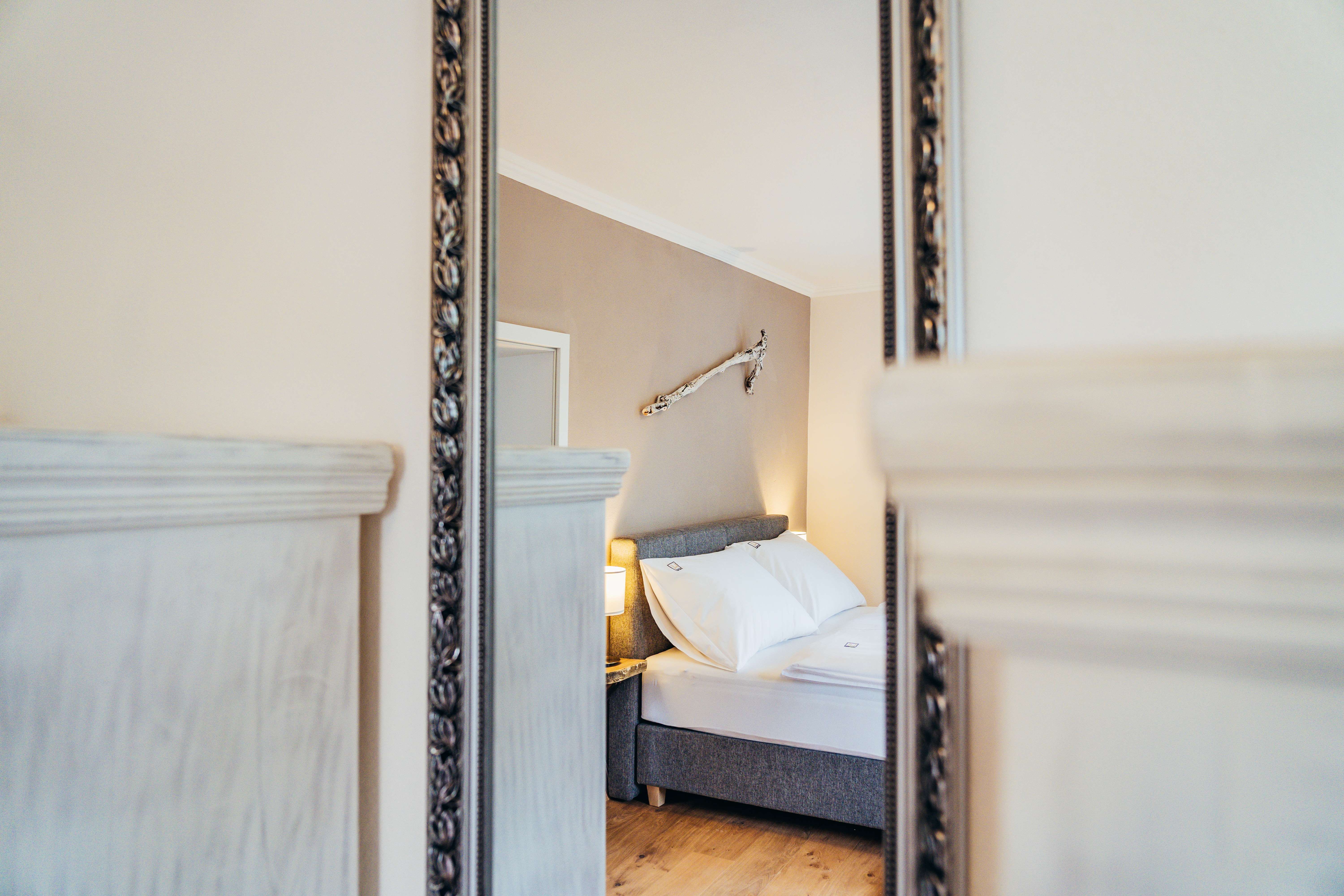 Zrkadlový obraz útulnej spálne s posteľou a nástennou dekoráciou.