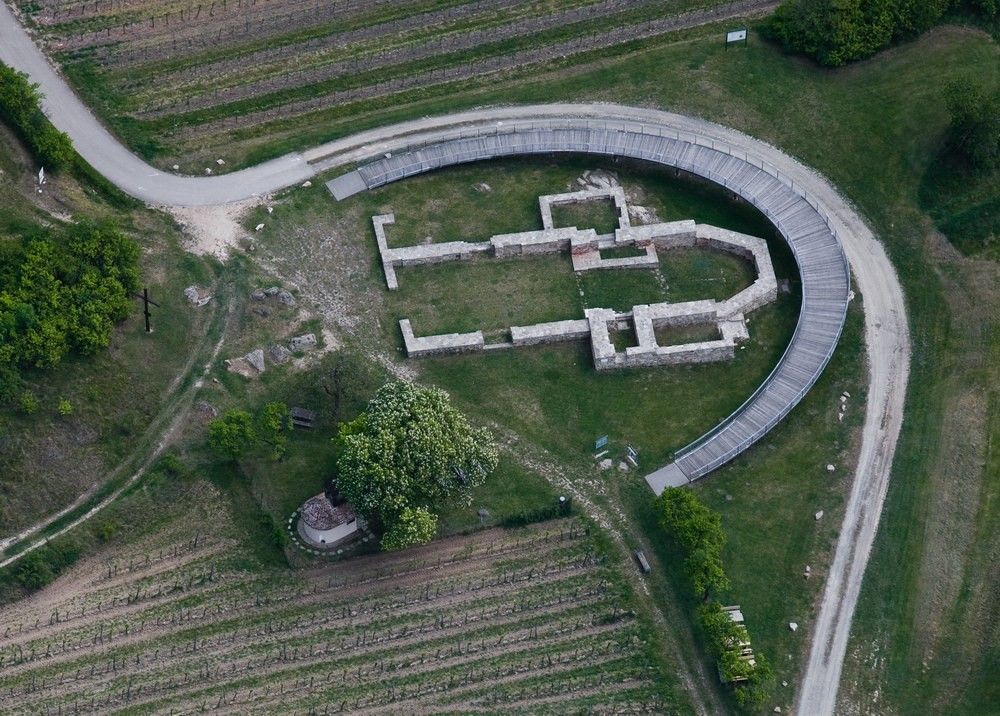 Letecký pohľad na miesto archeologických vykopávok s polkruhovou lávkou.