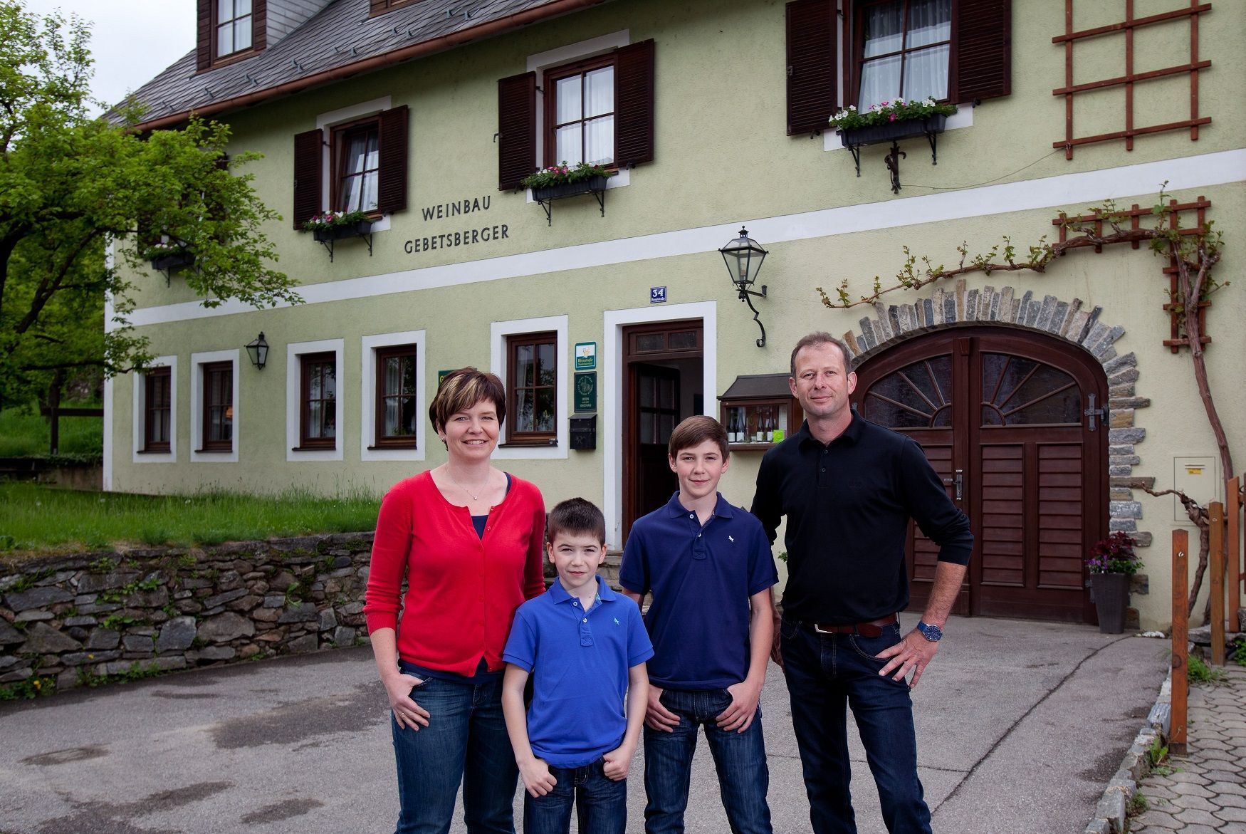 Rodina stojí pred budovou s nápisom "Weinbau Gebetsberger".