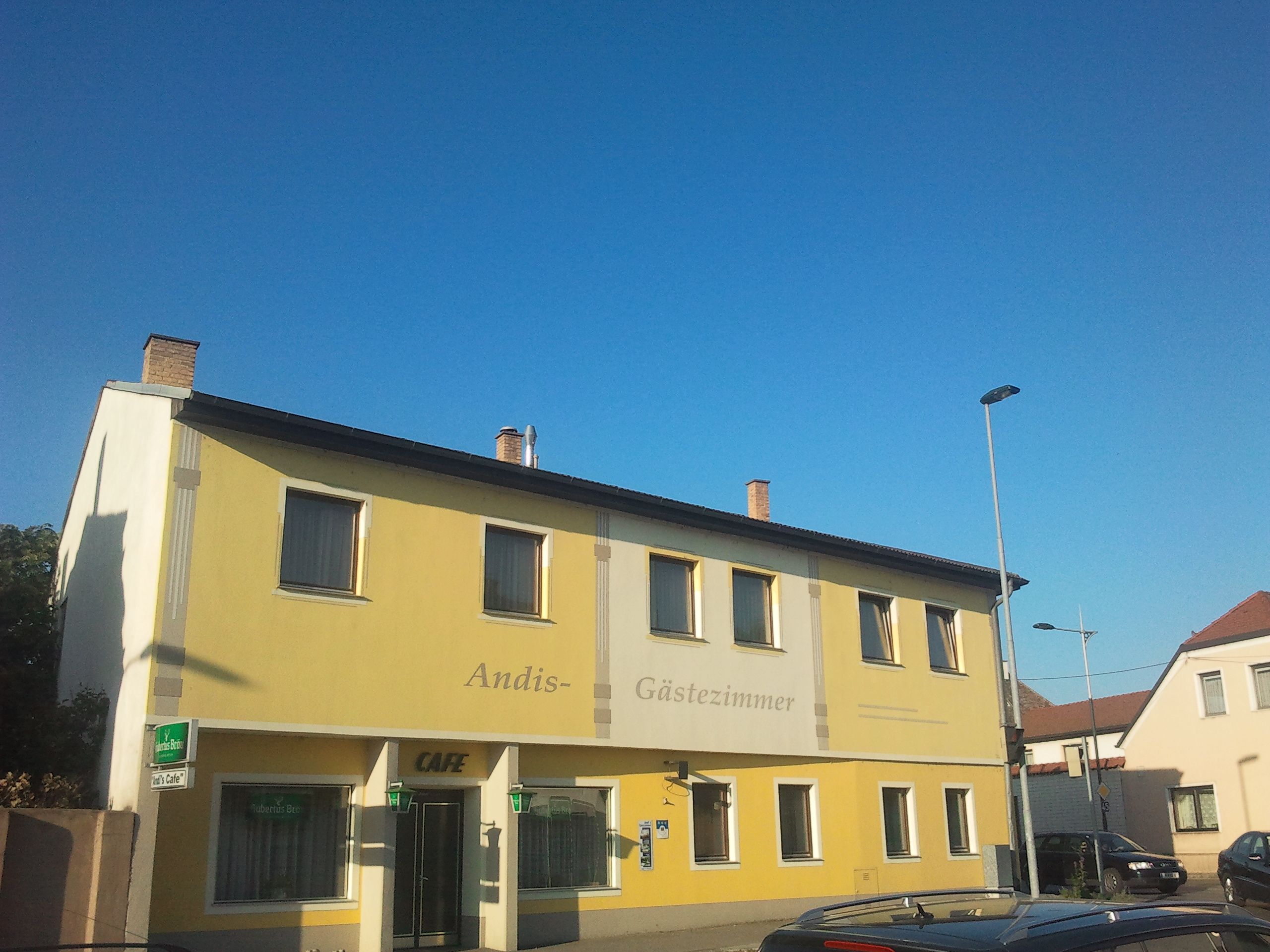 Žltá budova s označením "Andis Gästezimmer" a "Cafe".