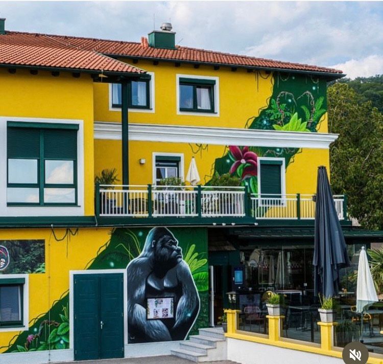 Žltá budova s nástennými maľbami goríl a motívmi džungle.
