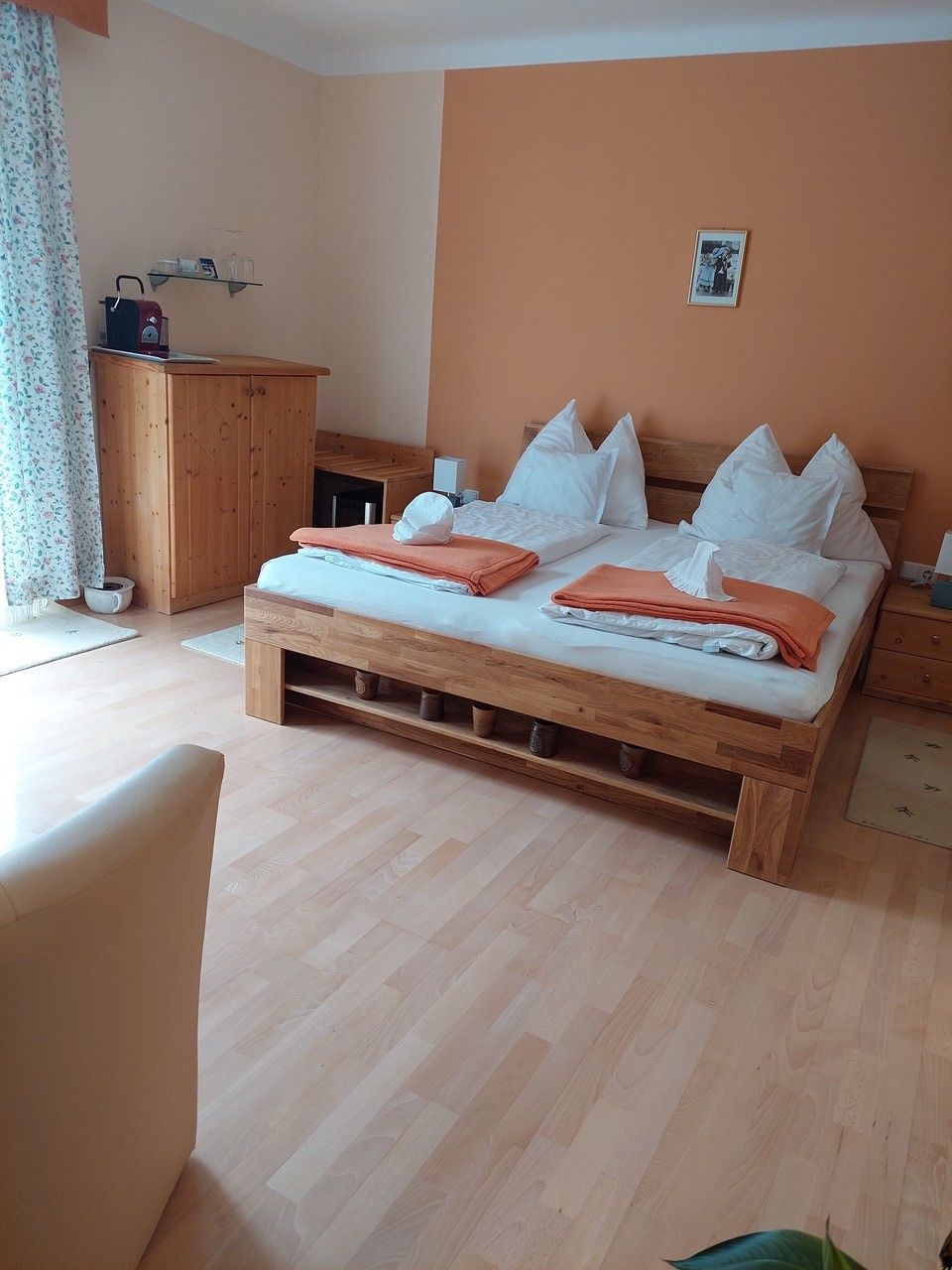 Útulná spálňa s manželskou posteľou, dreveným nábytkom a oranžovou stenou.
