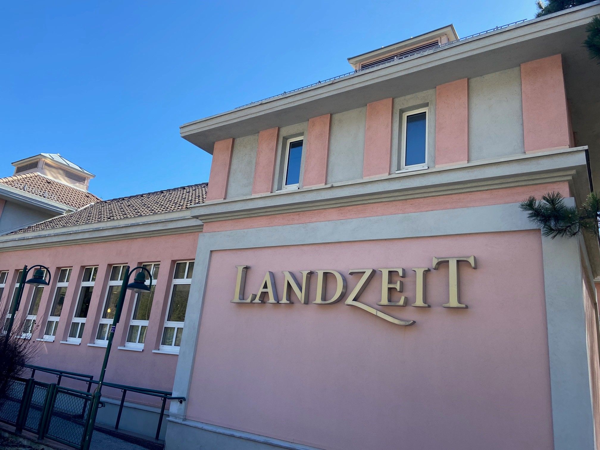 Budova s ružovou fasádou a nápisom "Landzeit".