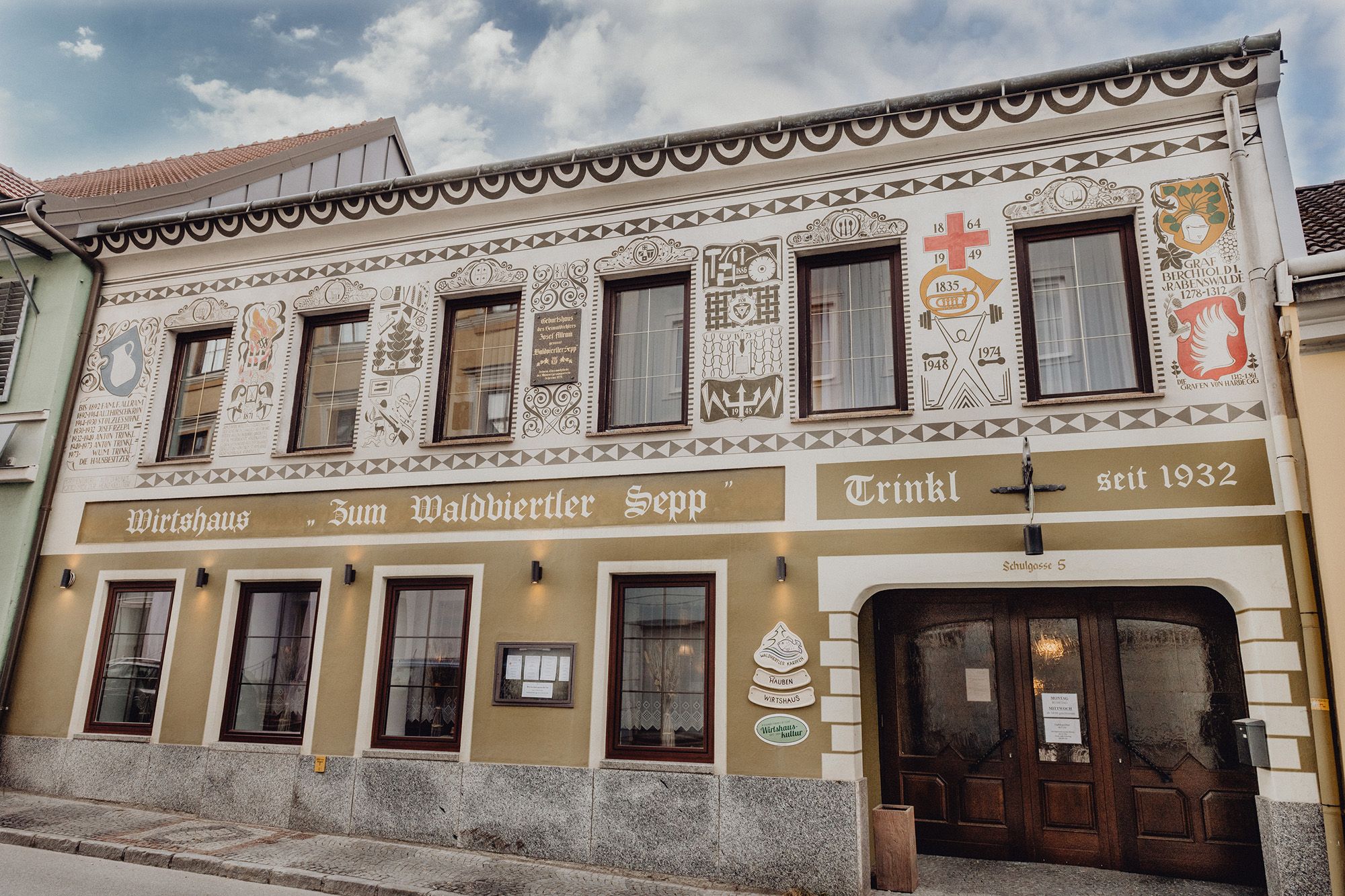 Fasáda tradičného hostinca s dekoratívnymi maľbami a nápisom "Zum Waldviertler Sepp" v obci Schrems.