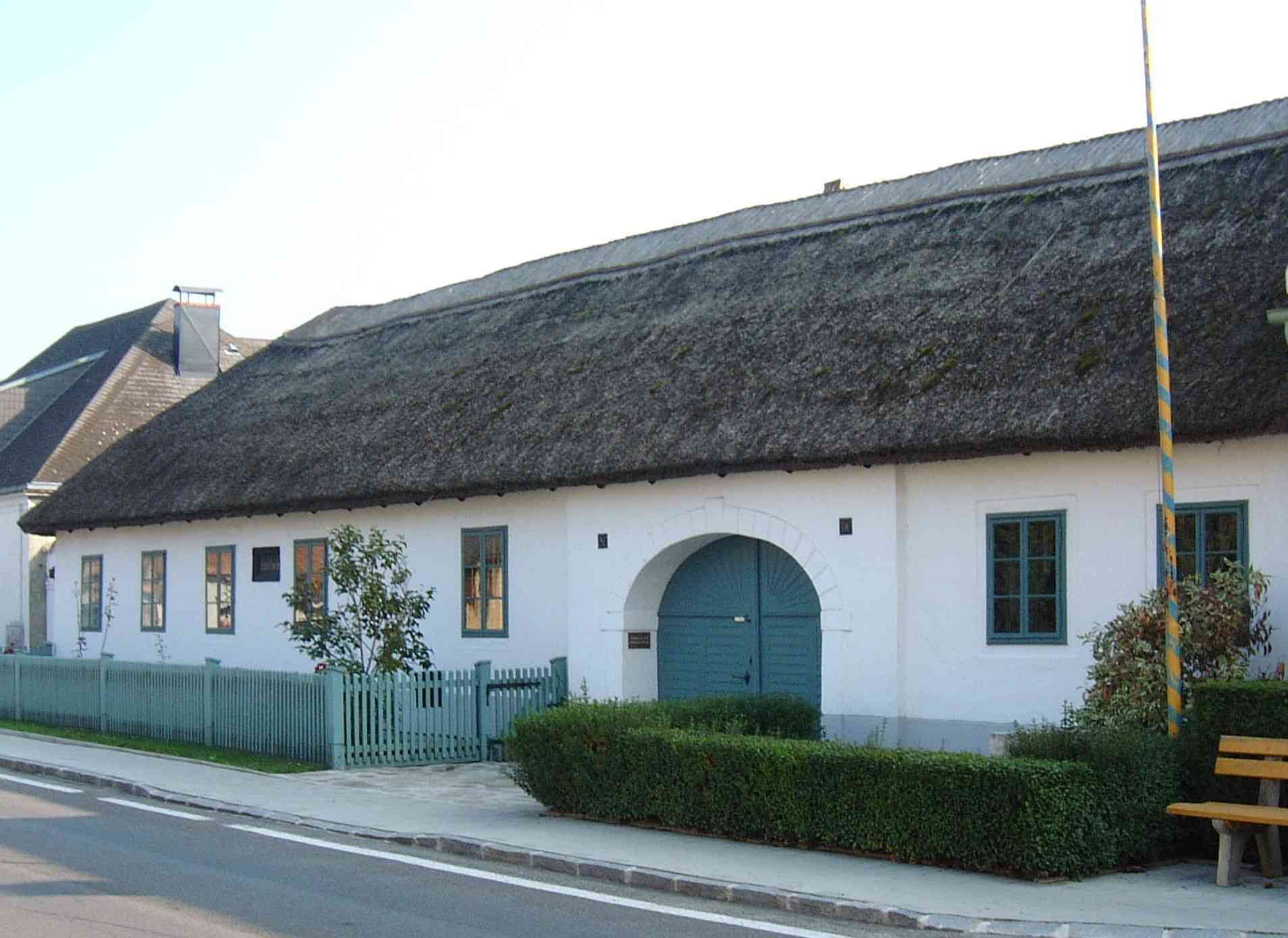 Rodný dom Josepha Haydna v rakúskom Rohrau so slamenou strechou a modrými oknami.