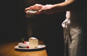 Tanier so šľahačkou a malinovým sorbetom, posypaný práškovým cukrom.