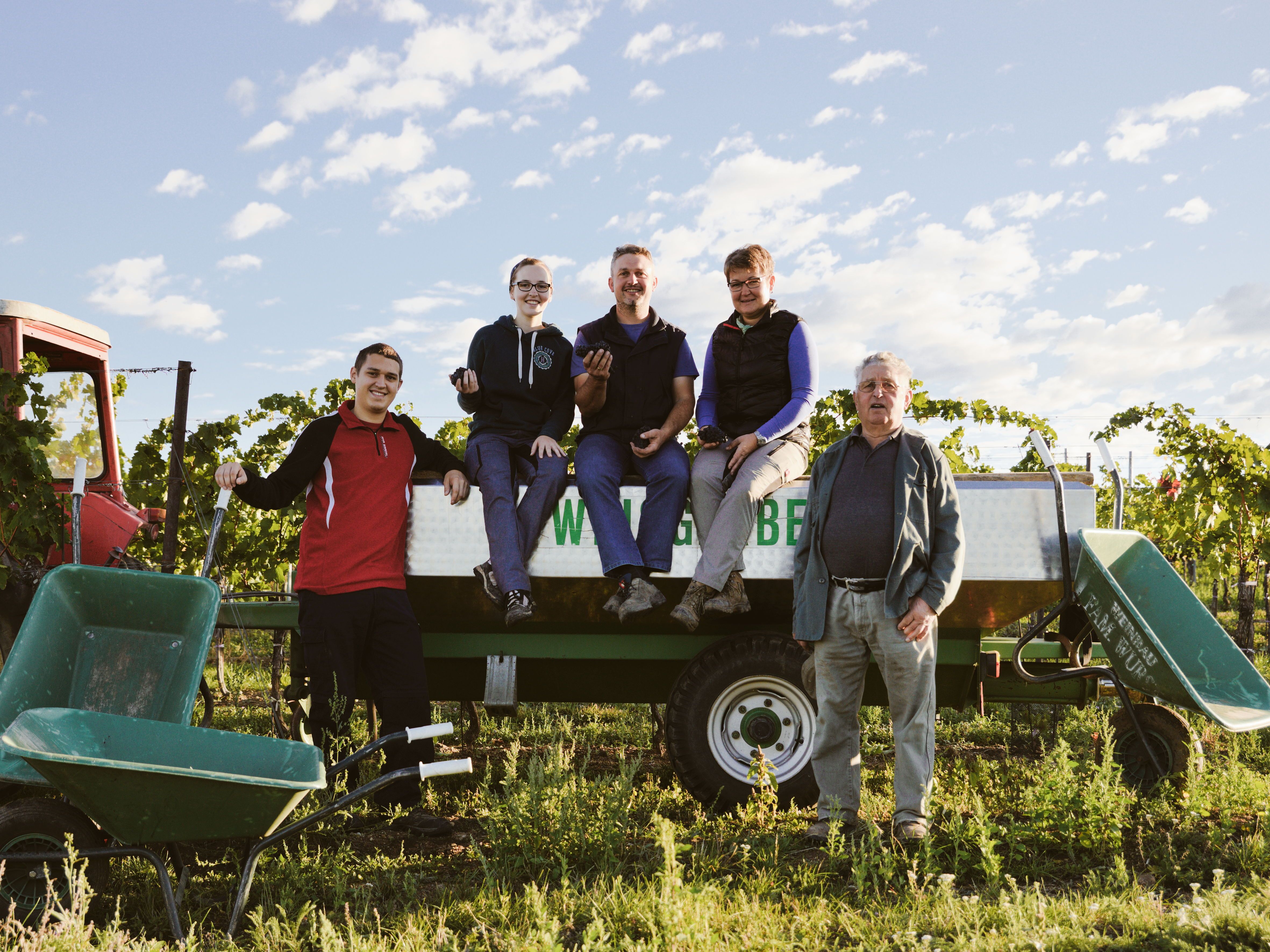 Rodina pózuje na traktorovom prívese vo vinohrade.